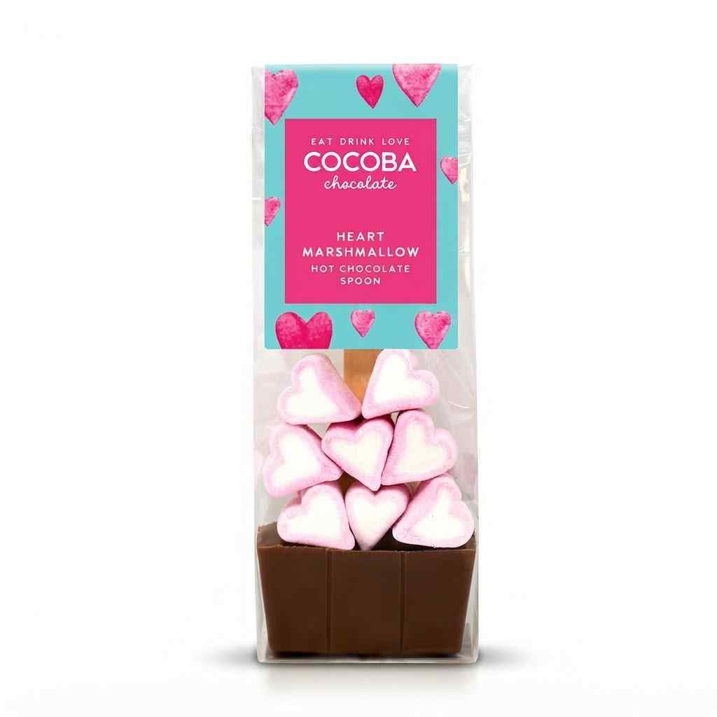A packaged chocolate hot chocolate spoon set in a clear bag, featuring a pink and teal label that reads 'Fat Chum Love COCOBA chocolate' and 'Heart Marshmallow Hot Chocolate Spoon.' The spoon base is dark brown chocolate, with several pink-and-white heart-shaped marshmallows stacked on top.