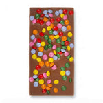A rectangle milk chocolate bar decorated with colorful candy-coated beans, shown on a plain white background.