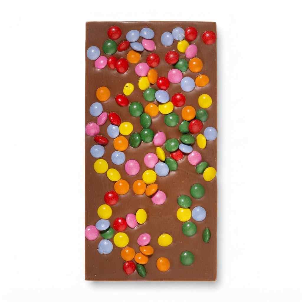 A rectangle milk chocolate bar decorated with colorful candy-coated beans, shown on a plain white background.