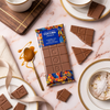 Cocoba chocolate bar with packaging on a marble surface with chocolate pieces and a spoon.