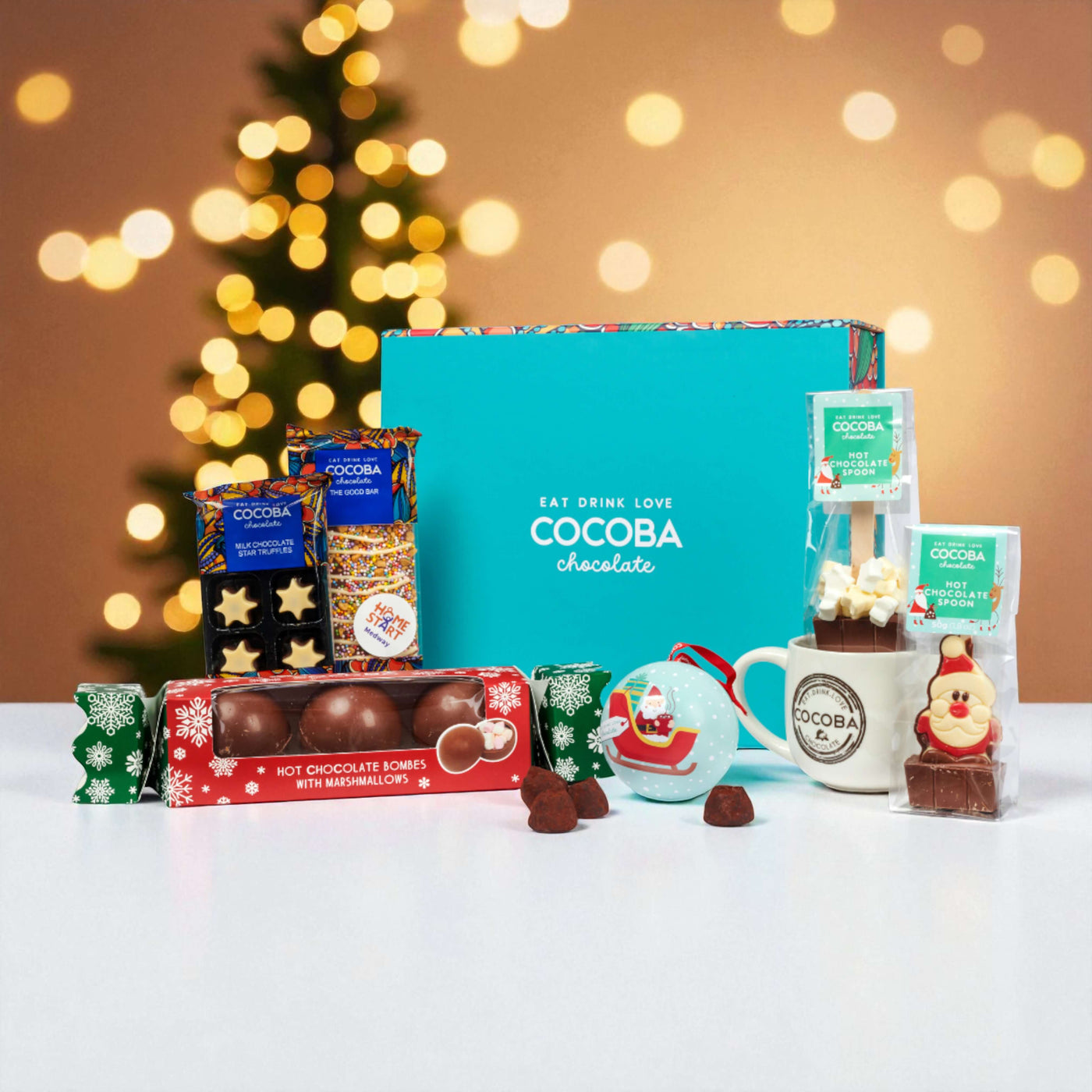 Cocoba chocolate products including a mug, packets, and hot chocolate bombs on a festive background.