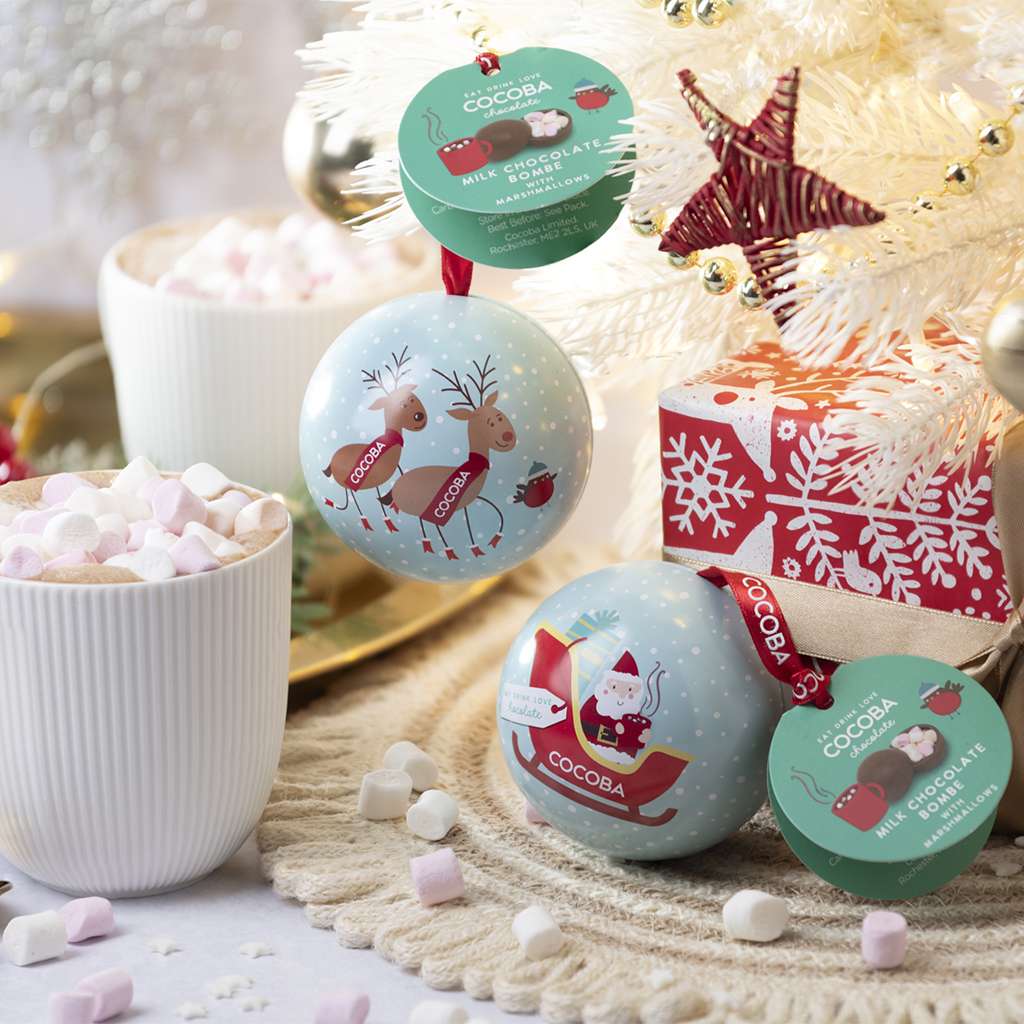 Christmas Hot Chocolate Bombe Baubles on a tree nwxt to gifts and a hot chocolate