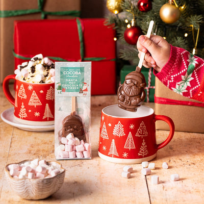 Christmas Santa Milk Chocolate Hot Chocolate Stirrer, surrounded by Christmas decorations and gifts.