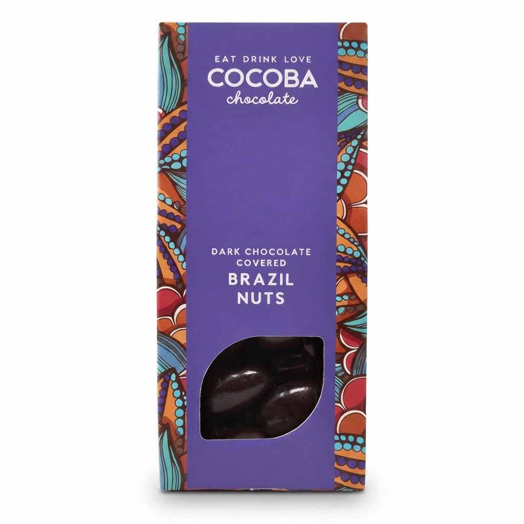 A package of Cocoba Chocolate Dark Chocolate Covered Brazil Nuts, featuring a purple front panel with a clear window showing the dark chocolate nuts inside, and colorful patterned borders on the sides.