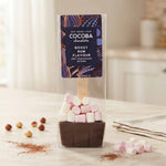 A packaged hot chocolate spoon in a clear plastic bag with a dark purple label reading 'COCOPA chocolate Boozy Rum Flavour'. The spoon inside is dipped in dark chocolate and topped with pink and white marshmallows.