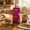 Cocoba chocolate buttons packaging on a wooden table with a bowl of chocolate buttons and a cup of coffee.
