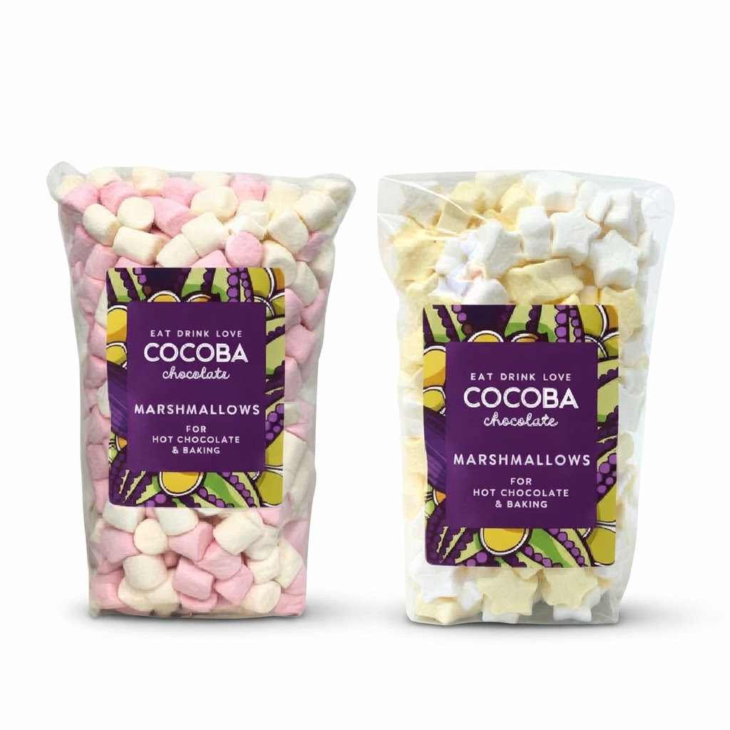 Two clear plastic bags of COCOBA chocolate marshmallows for hot chocolate and baking, one filled with pink and white marshmallows and the other with pale yellow and white marshmallows, shown on a white background.