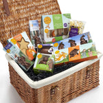 Wicker gift basket with assorted treats and snacks on a white background