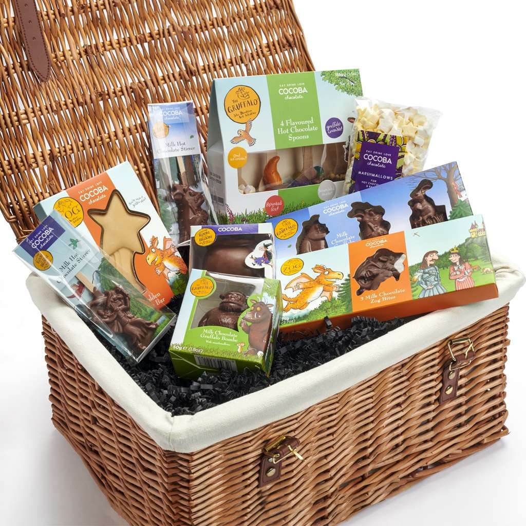 Wicker gift basket with assorted treats and snacks on a white background