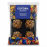 A package of Cocoba Chocolate Hazelnut Truffles in a clear plastic bag with a colorful label and patterned lower section. Four chocolate truffles are visible inside, each topped with chopped hazelnuts.