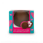 A boxed hot chocolate bomb with marshmallow hearts. The product is shown in its retail packaging, which features a turquoise and pink design with heart graphics and a clear window displaying the chocolate bomb inside.
