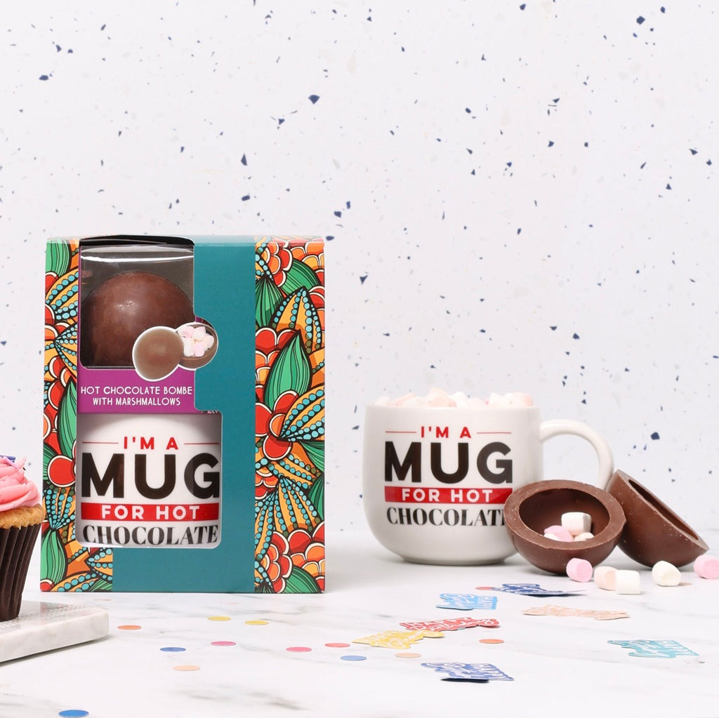 Hot chocolate mug and bomb gift set on a white surface with a colorful box.