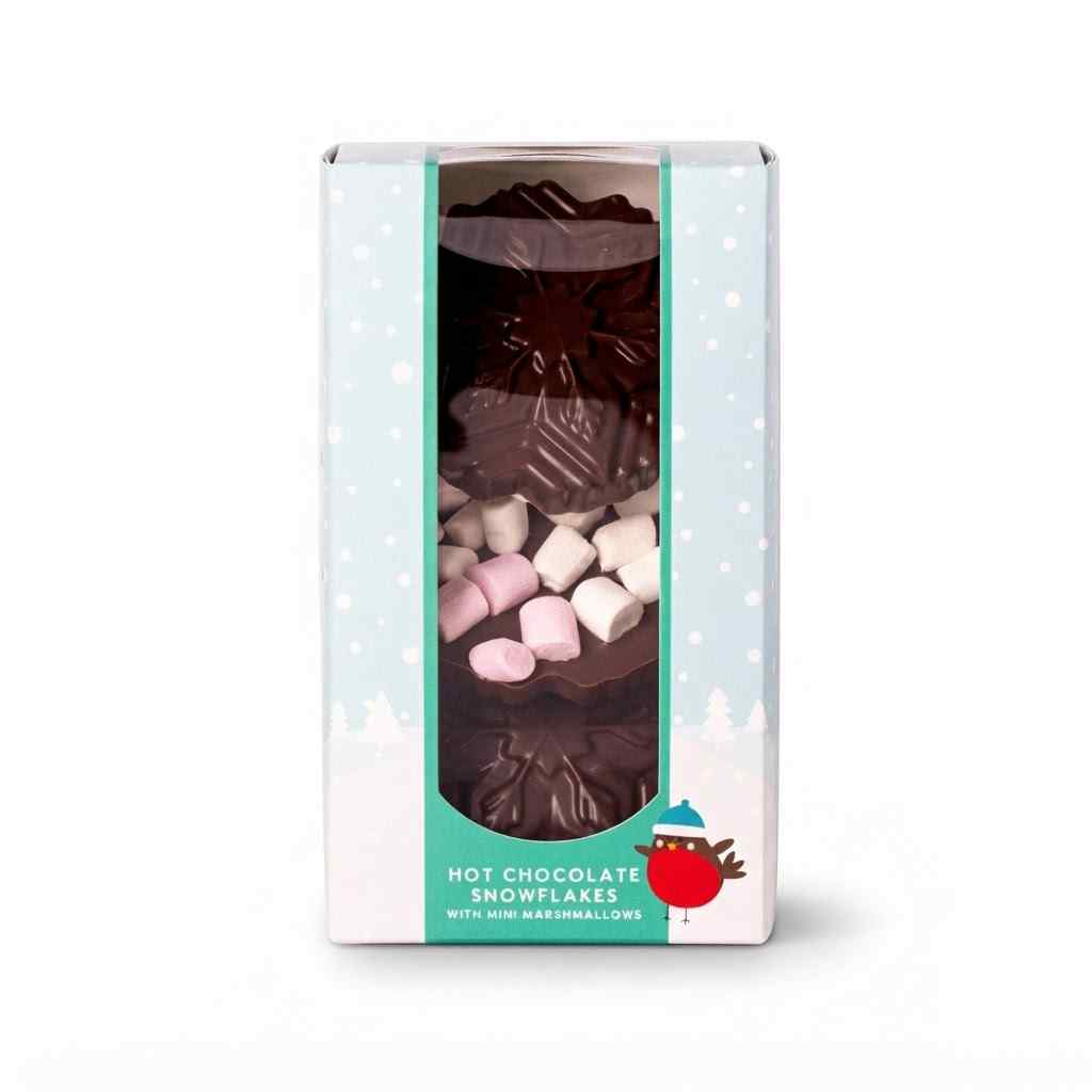 A boxed product of hot chocolate snowflakes with marshmallows, shown in a white and mint green package with a clear window displaying the dark chocolate snowflake pieces and pink and white marshmallows inside.