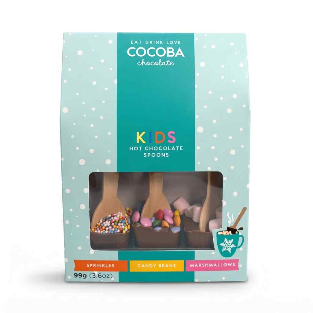 Cocoba Chocolate Kids Hot Chocolate Spoons in a light blue and teal bag with a clear window showing three chocolate spoons filled with sprinkles, candy beans, and marshmallows.