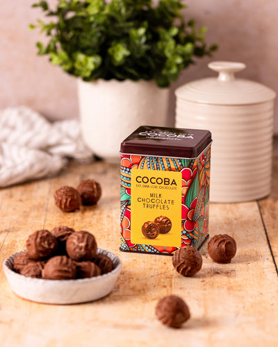 A bowl of Milk Chocolate Truffles next to the colourful Gift Tin they come in