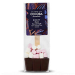 A packaged chocolate hot spoon in a clear plastic bag with a printed label. The product shows a dark brown chocolate base topped with pink and white marshmallows, with a wooden spoon handle visible inside.