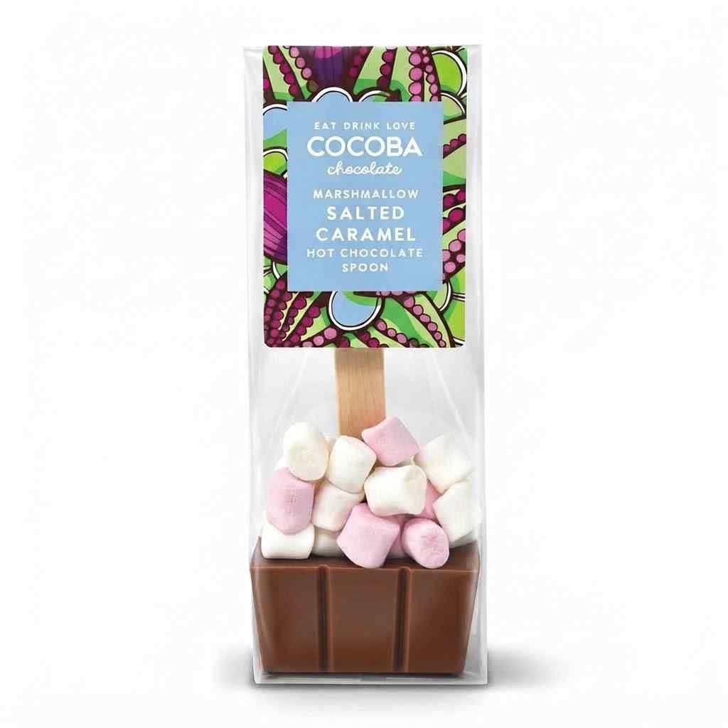 A packaged chocolate hot chocolate spoon from Cocoba Chocolate, featuring a brown chocolate base topped with pink and white marshmallows inside a clear plastic bag with a colorful label.