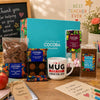 A Thank You Gift Set filled with chocolate, truffles and hot chocolate, with a Cocoba mug and gift box, with a teacher's desk in the background.
