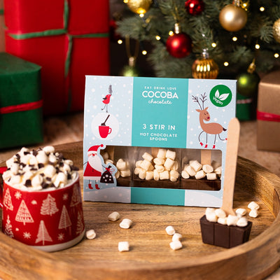 Cocoba's Vegan hot chocolate gift set with a festive background including a Christmas tree and presents.