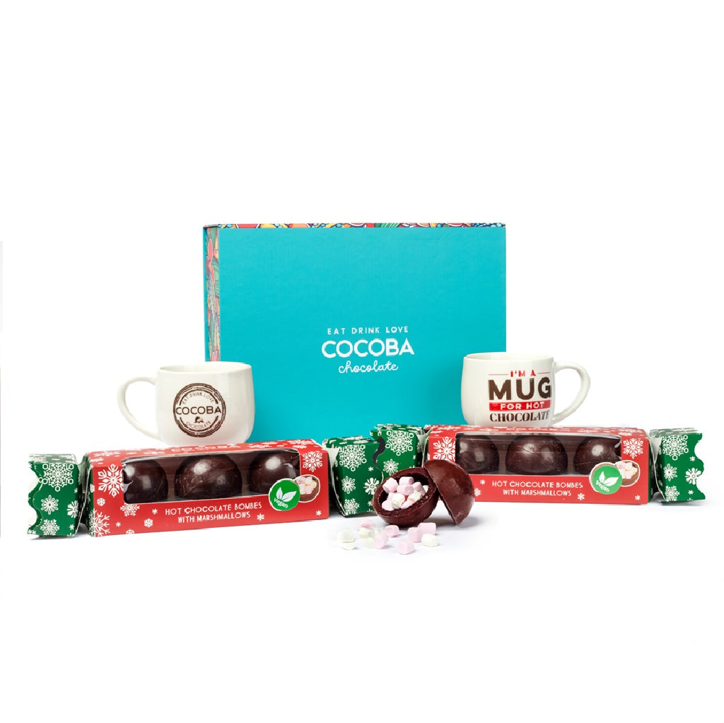 Two Cocoba Vegan hot chocolate bomb crackers with two Hot Chocolate mugs in a brightly colored Cocoba gift box