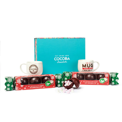 Two Cocoba Vegan hot chocolate bomb crackers with two Hot Chocolate mugs in a brightly colored Cocoba gift box
