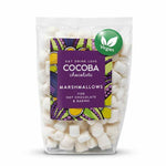 A clear stand-up pouch of Cocoba Chocolate Marshmallows for hot chocolate and baking, filled with small marshmallows. The front label is purple with colorful abstract patterns and a green circular Vegan badge near the top right.