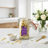 Jar of Cocoba white chocolate buttons on a kitchen counter with flowers and a bowl.
