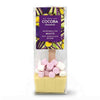 A packaged hot chocolate spoon from Cocoa Chocolate, featuring a pale yellow chocolate base with pink and white marshmallows on top, inside a clear bag with a purple label.