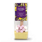 A packaged hot chocolate spoon from Cocoa Chocolate, featuring a pale yellow chocolate base with pink and white marshmallows on top, inside a clear bag with a purple label.