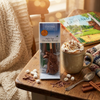 Mug of hot chocolate with whipped cream, a box of hot chocolate stirrer, and cinnamon sticks on a wooden table.